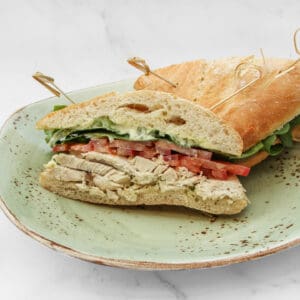 A fresh sandwich with turkey, tomato, and lettuce on a plate.