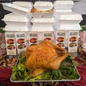 A roasted whole chicken on a bed of lettuce with spice packets in the background.