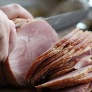 Sliced ham being cut with a knife.